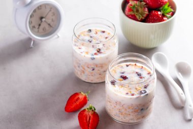 Granola, yoğurt ve çilek hafif beton arka planda kavanozlarda. Boşluğu kopyala.