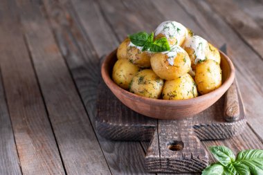 Ahşap bir arka planda seramik bir kasede dereotlu kızarmış patates.