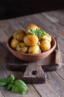 Ahşap arka planda seramik kasede fesleğenli kızarmış patates.