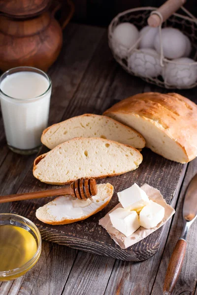 Sliced bread with butter and milk for breakfast on a wooden table