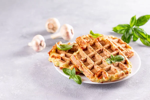 Zucchini waffle, zucchini fritters cooking on waffle maker, vegetarian zucchini waffles with basil and garlic in a plate