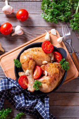 Tahta masada tavada servis edilen fesleğen ve domatesli tavuk budu. Üst görünüm, dikey.