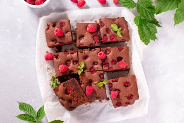 Koyu çikolatalı ev yapımı brovniler ve parlak gri arka planda ahududu, üst manzara, seçici odak