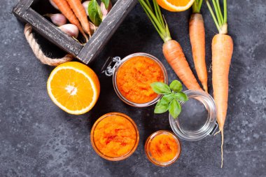 Koyu beton arka planda cam bir kavanozda turuncu ile havuç reçeli. Sebze reçeli. Korunma, hasat.