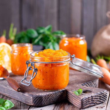 Ahşap bir masada cam bir kavanozda portakal suyu ile havuç reçeli. Kırsal