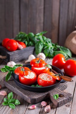 Tahta bir masada peynir ve fesleğenle doldurulmuş domates. Lezzetli yemek.