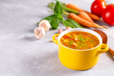 Hafif taşlı arka planda sarı tencereli baharatlı sebze çorbası. Sağlıklı yemek.