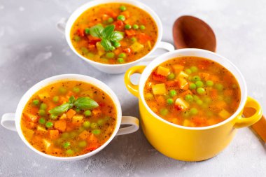 Hafif taşlı arka planda sarı tencereli baharatlı sebze çorbası. Sağlıklı yemek.