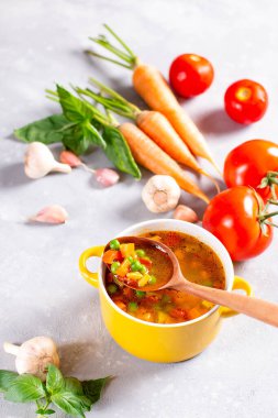 Sarı tencereli sebze çorbası ve hafif taşlı arka plan. Sağlıklı yemek.