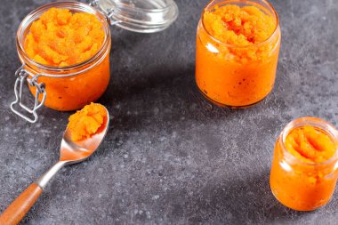 Koyu beton arka planda cam bir kavanozda portakal suyu ile kabak reçeli. Sebze reçeli. Korunma