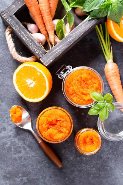 Home made carrot citrus jam on a wooden board on a dark concrete background. Vegetable jams. Preservation, top view