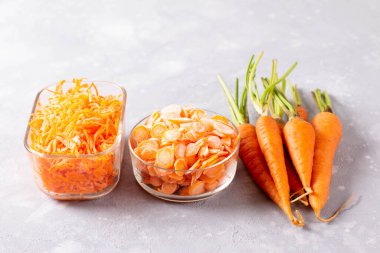 Hafif bir arka planda cam bir kabın içinde donmuş havuç dilimleri. Donmuş sebzeler