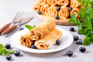 Beyaz tabakta süzme peynir ve böğürtlen dolu krepler. Sarılmış gözleme.