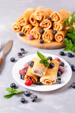 Süzme peynirli ince krepler. Lezzetli yuvarlanmış krep tabakta