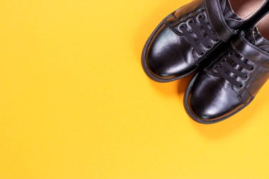 Sarı arka planda siyah ayakkabılar. Düz konum, üst görünüm modayı. Moda blogu bakışı. Üst Manzara. Boşluğu kopyala.