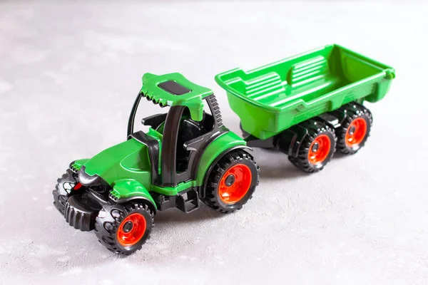 A green tractor. Toy for children. Toy tractor with the trailer