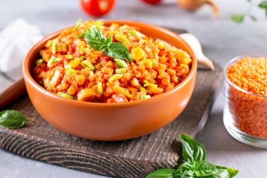 Arka planda fesleğen olan bir kasede vejetaryen mercimek yahnisi. Geleneksel Türk ya da Arap mercimek ve sebze baharatlı çorba, sağlıklı vejetaryen yemeği..