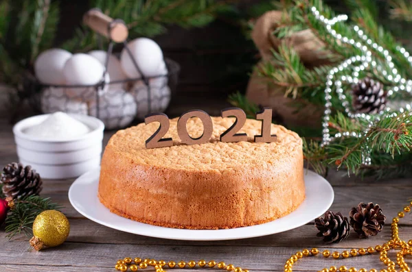 New Year and Christmas sponge cake or chiffon cake on white plate so soft and delicious with ingredients: eggs, flour, milk on wood table. Homemade bakery concept for background and wallpaper.