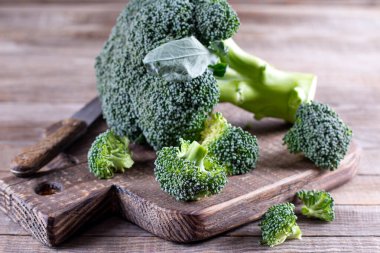 Brokoli tahtayı tahta bir bıçakla keserek parçalara ayırdı. Gıda konsepti, tazelik,