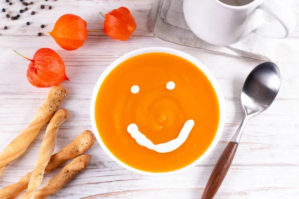 Funny food. Pumpkin puree soup with a smile as decoration, top view. The concept of baby food.
