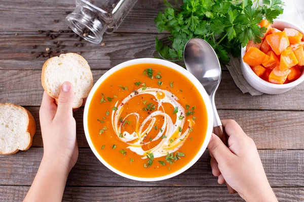 Flat-lay of kids hands and warming pumpkin cream soup with croutons on wooden background, top view. Autumn vegetarian, vegan, healthy comfort food, eating concept — Stock Image Flat Lay Kids Hands Warming Pumpkin Cream Soup Croutons Wooden Stock Picture