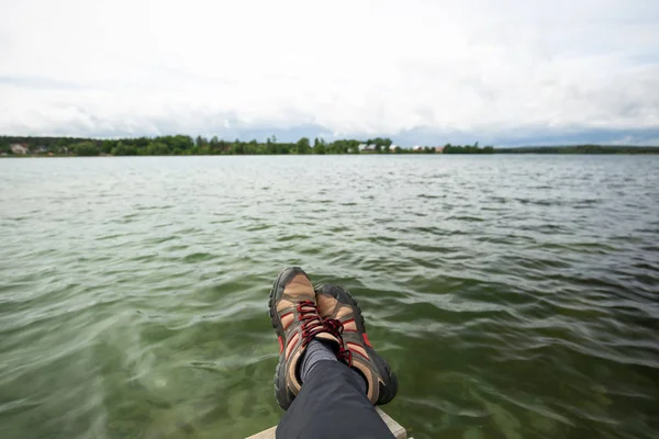 View of two crossed feet and the lake and sky