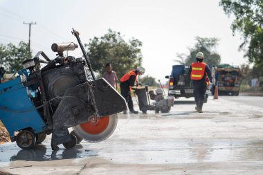 Kum kamyonuna yağmur yağarken beton yol kesiciler arka planı bulanıklaştırdı, inşaat konsepti