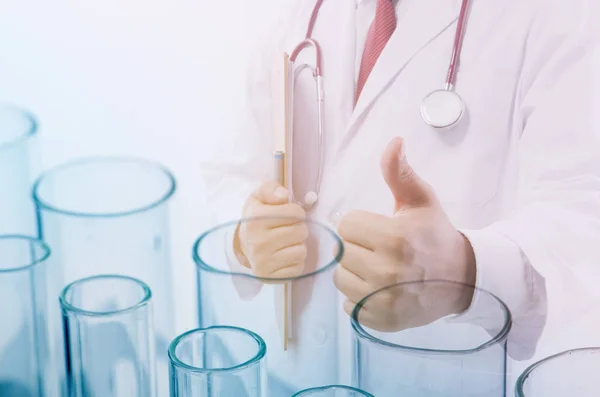 Çifte teşhirci doktor not alıyor. Doktorun konsept ışığı, laboratuvarda kimyasal element