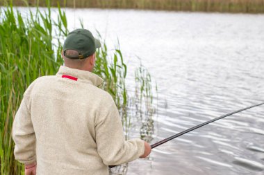 Bir adam nehrin arka planında bir balık yakalar..