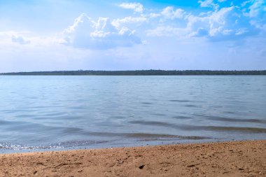 Kumsal ve nehir. Bulutlu gökyüzünün arkaplanındaki manzara nehri.