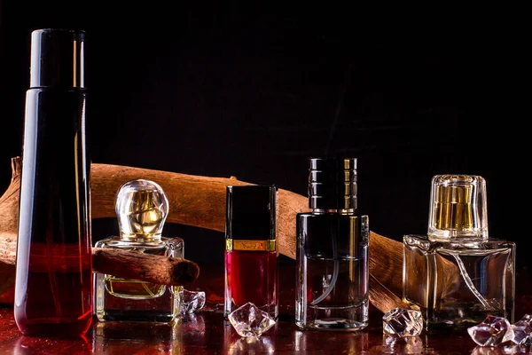 The perfume bottles are on the table.Perfume on a background of wooden driftwood and ice cubes.
