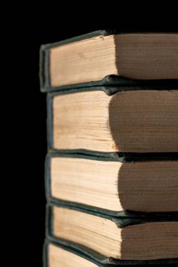 Siyah arka planda bir yığın eski kitap.