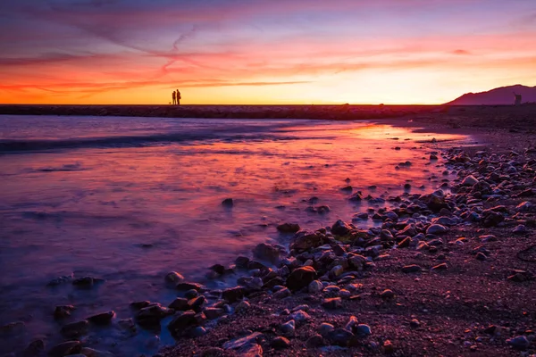Renkli günbatımında iskelede duran çift