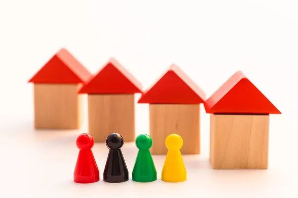 four meeple standing in front of four shifted wooden houses