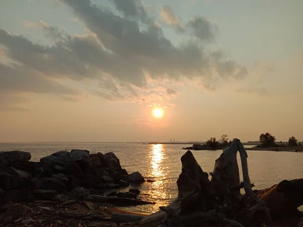 金色的落日在海面上 城市在地平线上清晰可见 天空中有美丽的云彩 水面上也闪烁着光芒 — 图库照片