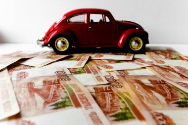 Rus para banknotlarının arka planında kırmızı oyuncak araba. Veresiye ve taksitle yeni bir araba almak. Üzerinde 5000 ruble yazan Rus banknotları. Kapatın. İş, finans kavramı. İzole edilmiş