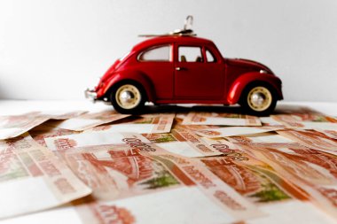 Rus para banknotlarının arka planında kırmızı oyuncak araba. Veresiye ve taksitle yeni bir araba almak. Üzerinde 5000 ruble yazan Rus banknotları. Kapatın. İş, finans kavramı. İzole edilmiş