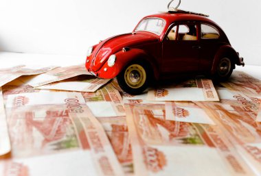 Rus para banknotlarının arka planında kırmızı oyuncak araba. Veresiye ve taksitle yeni bir araba almak. Üzerinde 5000 ruble yazan Rus banknotları. Kapatın. İş, finans kavramı. İzole edilmiş