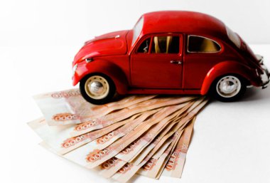 Rus para banknotlarının arka planında kırmızı oyuncak araba. Veresiye ve taksitle yeni bir araba almak. Üzerinde 5000 ruble yazan Rus banknotları. Kapatın. İş, finans kavramı. İzole edilmiş