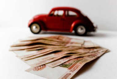 Rus para banknotlarının arka planında kırmızı oyuncak araba. Veresiye ve taksitle yeni bir araba almak. Üzerinde 5000 ruble yazan Rus banknotları. Kapatın. İş, finans kavramı. İzole edilmiş