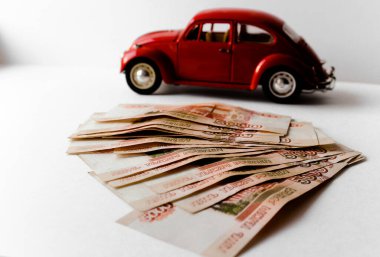 Rus para banknotlarının arka planında kırmızı oyuncak araba. Veresiye ve taksitle yeni bir araba almak. Üzerinde 5000 ruble yazan Rus banknotları. Kapatın. İş, finans kavramı. İzole edilmiş