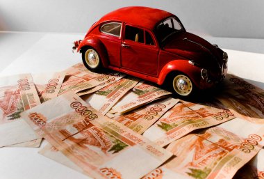 Rus para banknotlarının arka planında kırmızı oyuncak araba. Veresiye ve taksitle yeni bir araba almak. Üzerinde 5000 ruble yazan Rus banknotları. Kapatın. İş, finans kavramı. İzole edilmiş