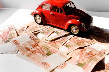 Rus para banknotlarının arka planında kırmızı oyuncak araba. Veresiye ve taksitle yeni bir araba almak. Üzerinde 5000 ruble yazan Rus banknotları. Kapatın. İş, finans kavramı. İzole edilmiş