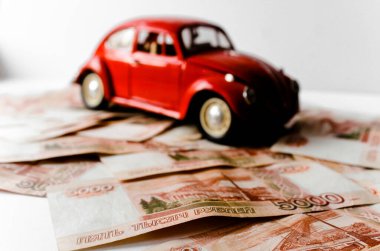 Rus para banknotlarının arka planında kırmızı oyuncak araba. Veresiye ve taksitle yeni bir araba almak. Üzerinde 5000 ruble yazan Rus banknotları. Kapatın. İş, finans kavramı. İzole edilmiş