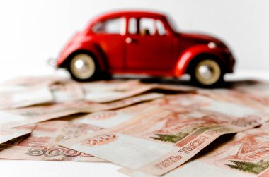 Rus para banknotlarının arka planında kırmızı oyuncak araba. Veresiye ve taksitle yeni bir araba almak. Üzerinde 5000 ruble yazan Rus banknotları. Kapatın. İş, finans kavramı. İzole edilmiş