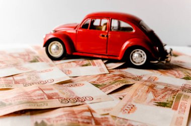 Rus para banknotlarının arka planında kırmızı oyuncak araba. Veresiye ve taksitle yeni bir araba almak. Üzerinde 5000 ruble yazan Rus banknotları. Kapatın. İş, finans kavramı. İzole edilmiş