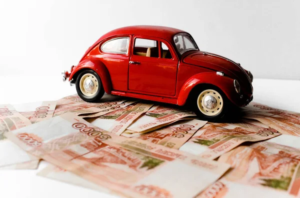Red toy car on the background of Russian money bills. Buying a new car on credit and by installments.Russian banknotes with inscription of 5000 rubles. Close up. Business, finance concept. Isolated