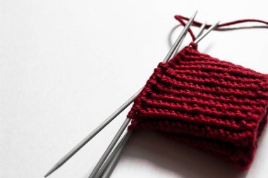 Bitmemiş örgü yünü ve örgü iğneleri projesi. Kırmızı iplik ve arapsaçı. El yapımı konsept. El işi afişi. İzole edilmiş. Yukarıdan bak. Üst Manzara. Boşluğu kopyala