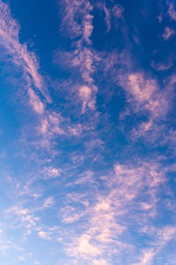 Mavi bir arka planda ince turuncu renkli günbatımı bulutlarının vücutları.