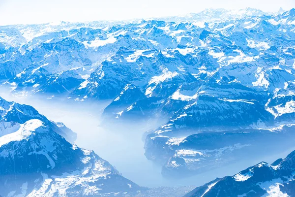 Planeta azul tierra panorama aéreo alpino único. Vista aérea de gran altitud de los lagos de los Alpes Swiiss de Europa central cubiertos de nieve, vista desde una ventana de cabina de avión. Concepto de conservación ambiental. — Foto de Stock